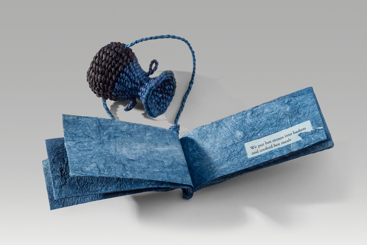 A basket is a reminder (blue version) (2022). Indigo dye in paper thread and paper cord, on corded and twined hanji, combined with joomchi and inkjet print on hanji. Basket: 2.6 x 2 x 2.25”; book: 2 x 5 x 0.4” closed. One of a kind.