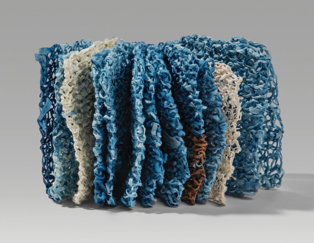 Trip (knitted version) (2025). Indigo, persimmon juice, letterpress, and pen on hanji. 4.5 x 3.75 x 3” closed, 8.5” wide open. Variable edition of 18.